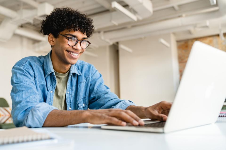 An investor smiles while looking at something on a laptop.