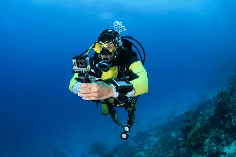 A scuba diver with a camera in the ocean exploring.