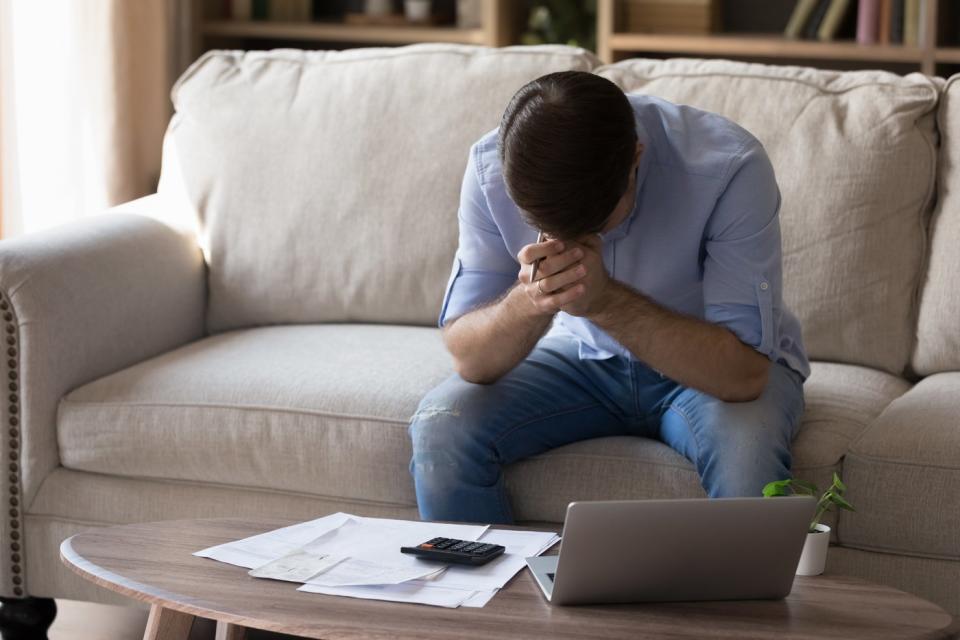 Person with head down, sitting on a sofa. 