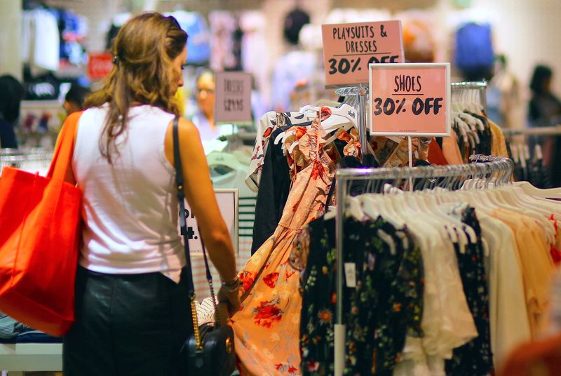 © Reuters. A shopper touches a dress as she inspects clothes on display next to sale signs at a retail store in central Sydney, Australia, October 25, 2017.     REUTERS/Steven Saphore/file photo