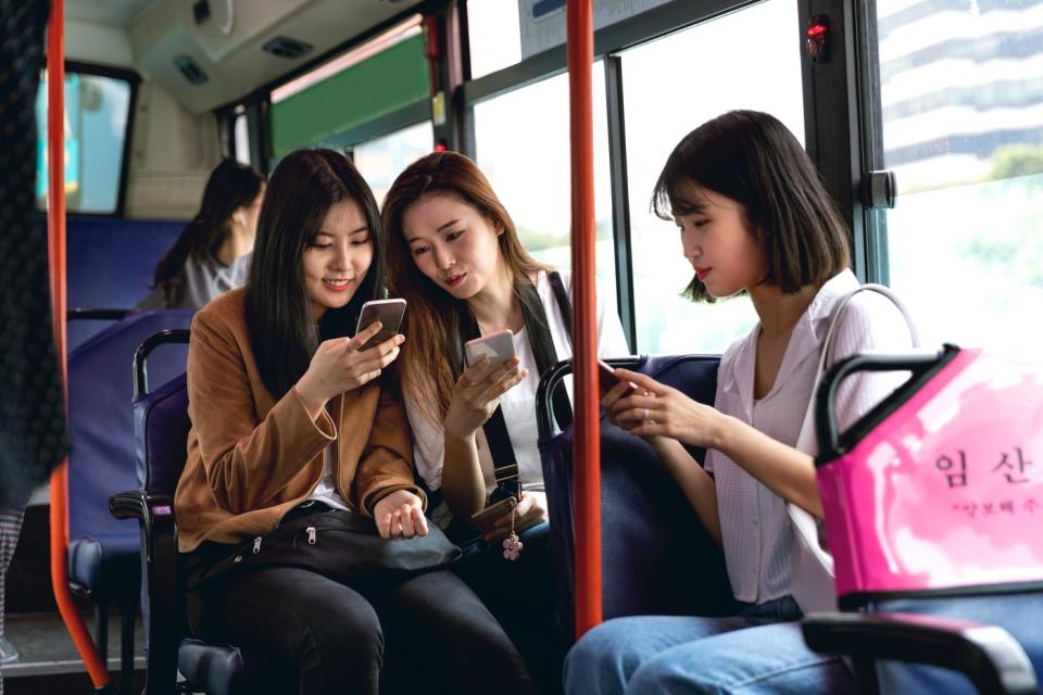 Passengers on a bus checking out their phones.