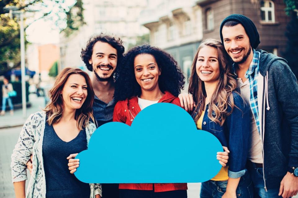 Five young professionals hold up a cardboard cutout of a cloud.